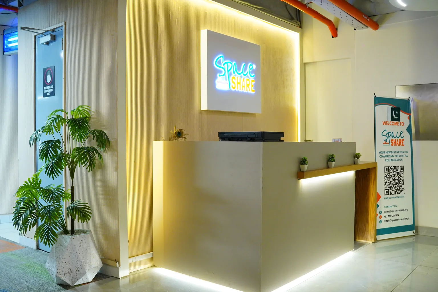 The SpaceShare reception desk under a lit neon logo