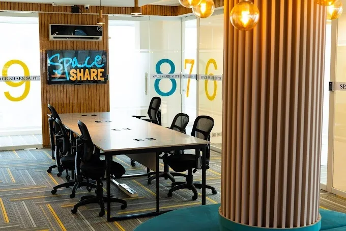 A boardroom table beside glass suites numbered 6 to 9, with a ribbed timber column