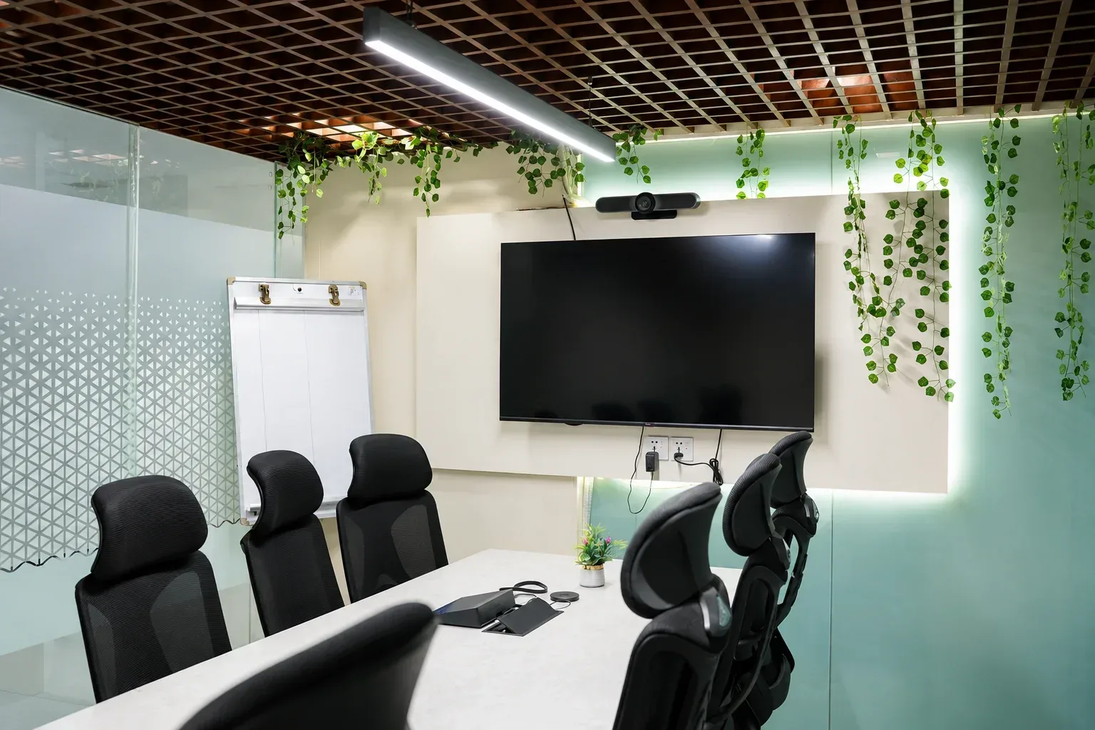 A meeting room with a long boardroom table, mesh chairs and a window along one wall