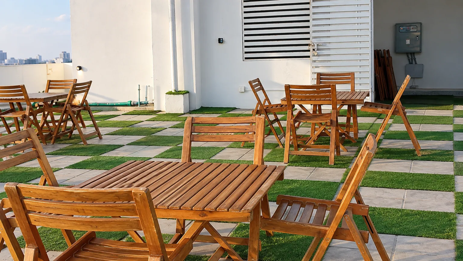 Folding wooden tables and chairs set out on the DHA Phase 8 rooftop in the afternoon sun