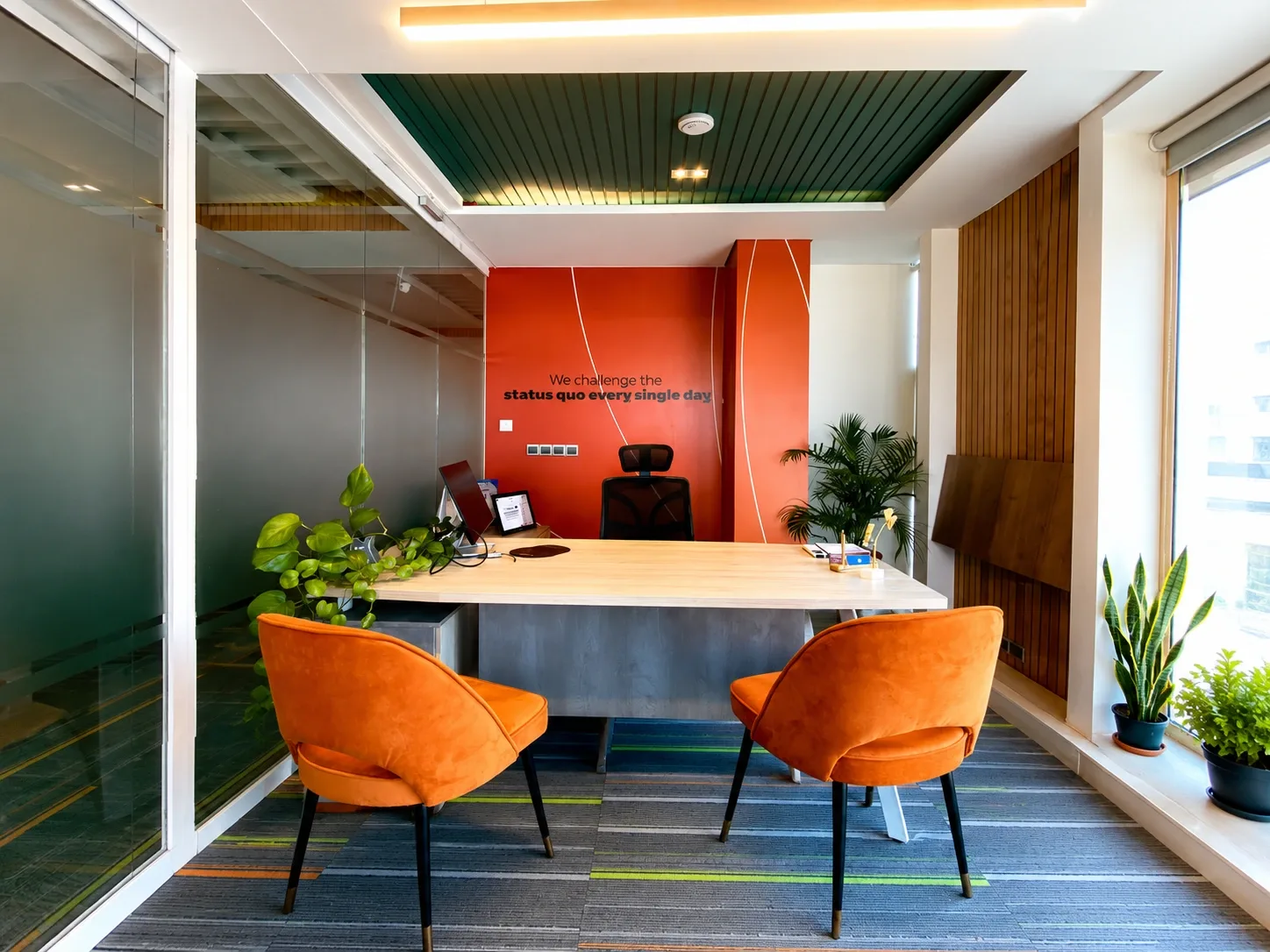 A desk with orange chairs in front of an orange feature wall